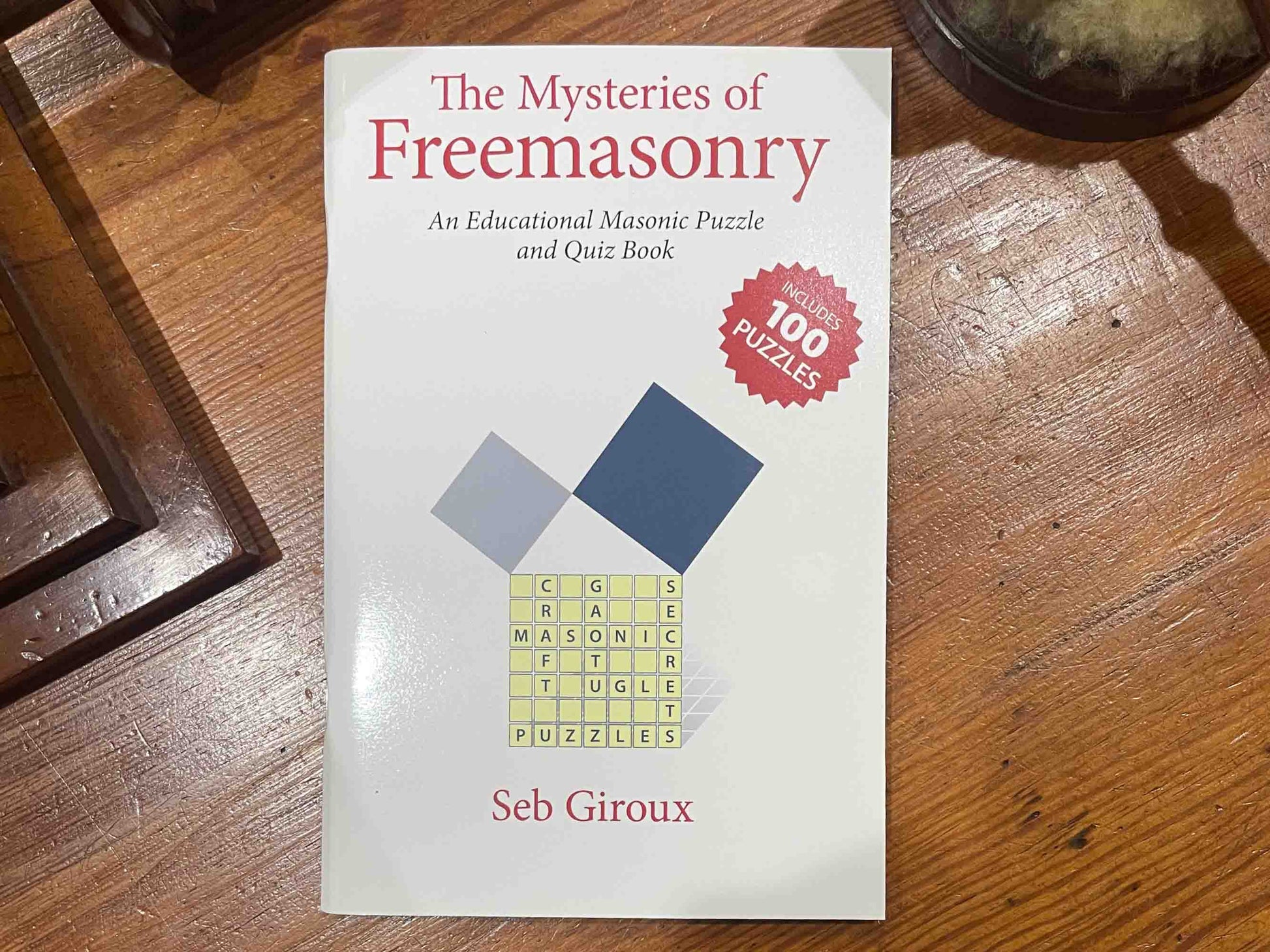 The Mysteries of Masonry (Puzzle Book): The Mysteries of Masonry book cover, featuring a compass and square, symbols often associated with Freemasonry, with the title of the book prominently displayed.